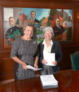 Peggy Steinman, left, and Pamela Thye, co-chairs of the Steinman Foundation, stand in front of a portrait of the patriarchs of the Steinman family.