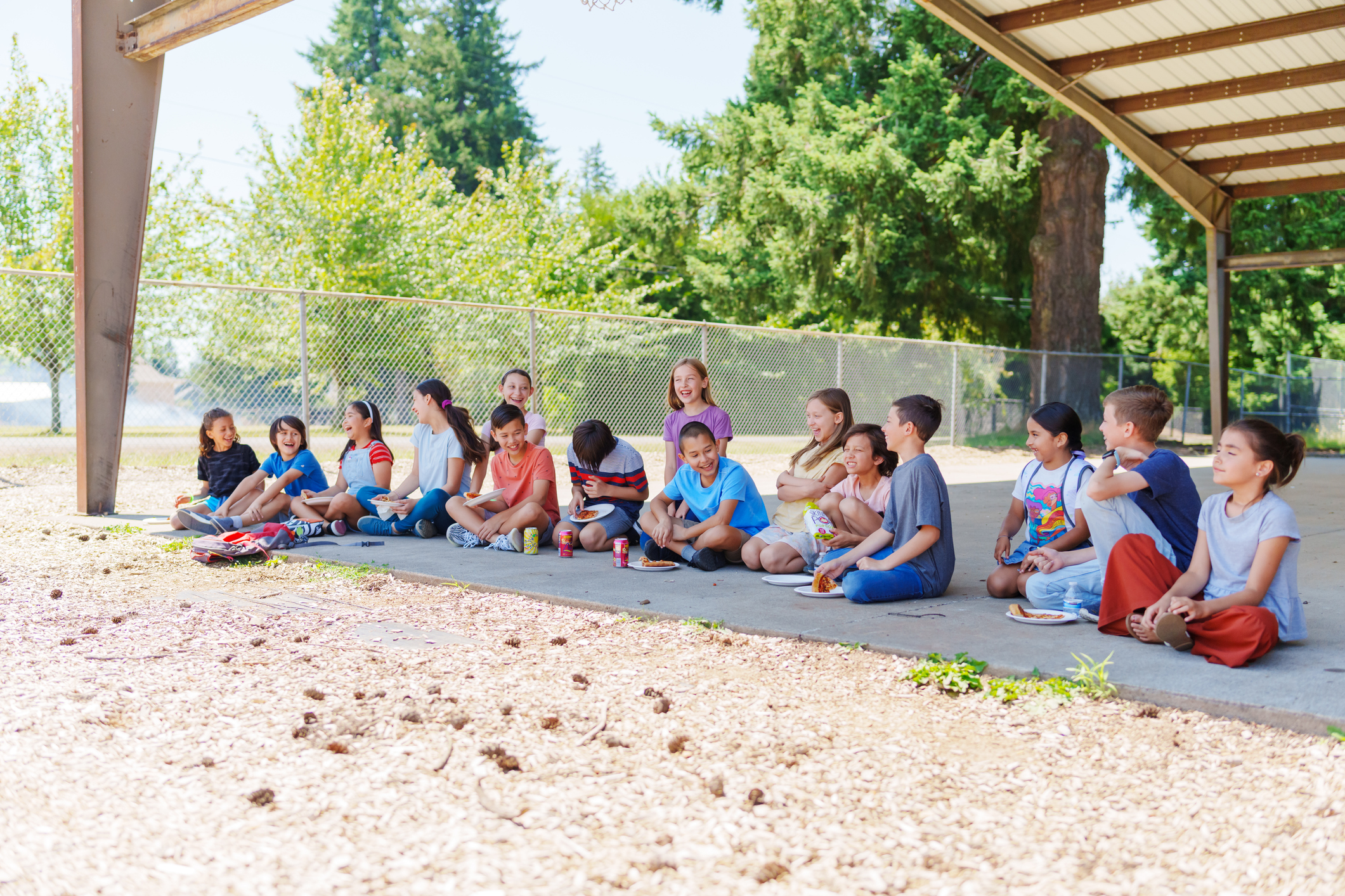 Group of students eating lunch outside in schoolyard